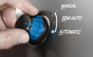Une main tourne un cadran bleu sur un panneau de commande. Le panneau affiche trois options : « MODE MANUEL », « MODE SEMI-AUTO » et « MODE AUTOMATIQUE », avec le voyant lumineux à côté de « MODE AUTOMATIQUE ».