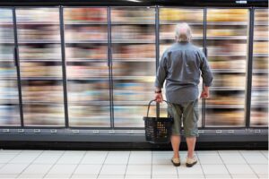 Man standing in front of supermarket shelves, trying to calculate true demand