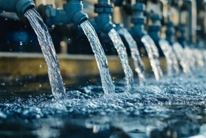 A row of pipes releasing streams of water into a reservoir, illustrating a water filtration or supply system.