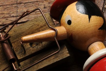 Wooden Pinocchio's nose caught in a mouse trap