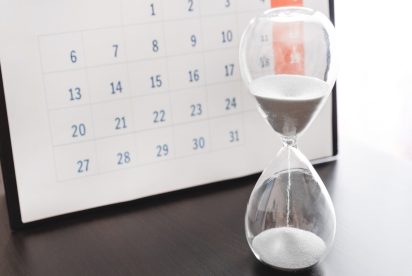hourglass in front of calendar page, representing end-of-the-month demand signal distortion